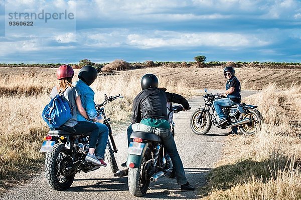 Rückansicht von vier Freunden  die sich auf Motorrädern auf der Landstraße unterhalten  Cagliari  Sardinien  Italien