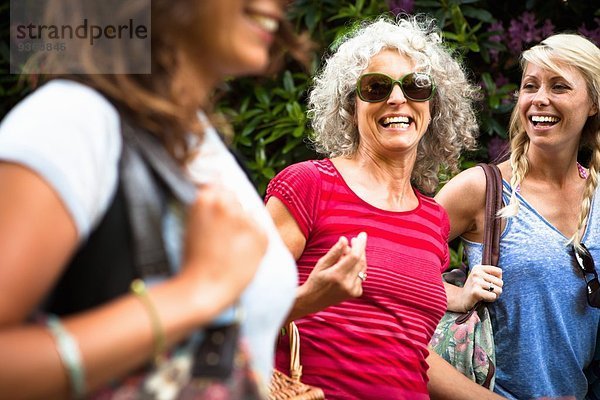 Reife Mutter und zwei Töchter lachend und plaudernd beim Gehen