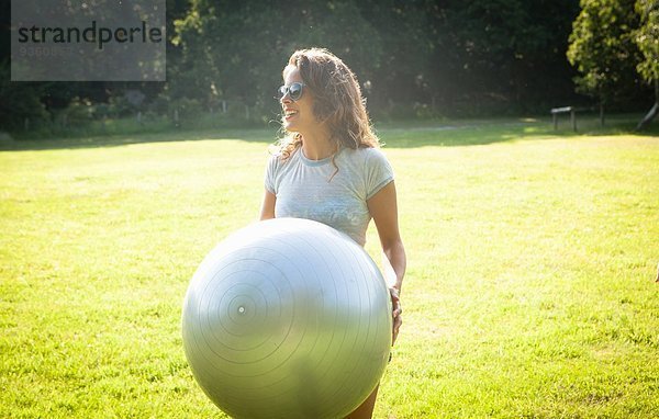 Mittlere erwachsene Frau  die den Übungsball im Feld hochhält