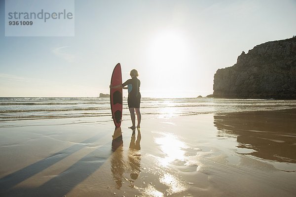 Silhouettierte Seniorin am Strand stehend mit Surfbrett  Camaret-sur-mer  Bretagne  Frankreich