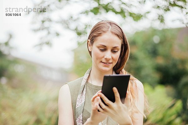 Junge Frau mit Touchscreen auf digitalem Tablett im Feld