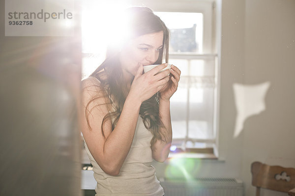 Porträt einer jungen Frau beim Tee trinken am Morgen