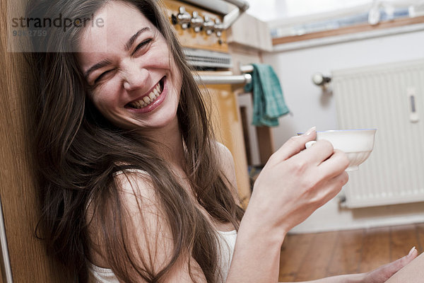 Porträt einer lächelnden jungen Frau mit einer Tasse Tee zu Hause