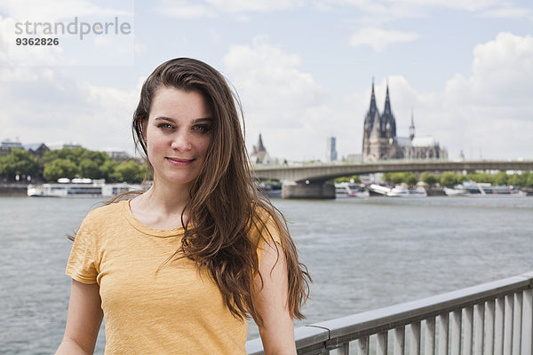 Deutschland  Köln  Porträt einer lächelnden jungen Frau vor der Rheinschiene