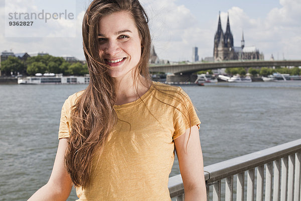 Deutschland  Nordrhein-Westfalen  Köln  Portrait einer lächelnden jungen Frau vor dem Rhein