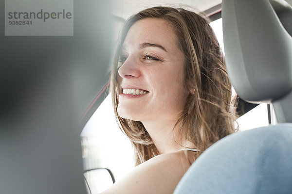 Porträt einer lächelnden jungen Frau  die in einem Auto sitzt