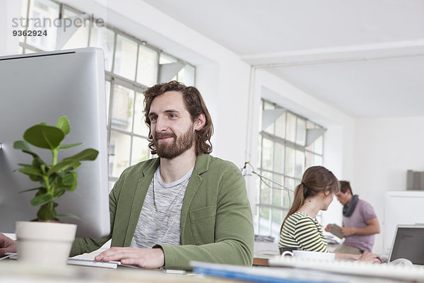 Porträt eines jungen Mannes am Computer in einem Kreativbüro