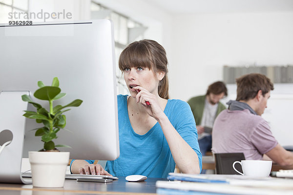 Porträt einer jungen Frau am Computer in einem Kreativbüro