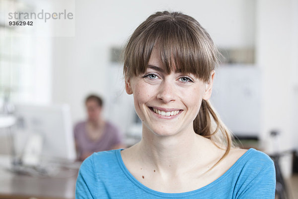 Porträt einer lächelnden jungen Frau in einem Kreativbüro