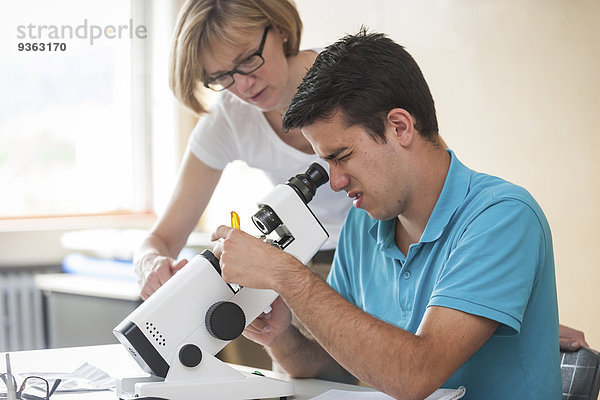 Lehrer mit Berufsschüler mit Optikergerät