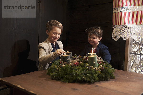 Zwei kleine Jungen entzünden Kerzen auf einem Adventskranz