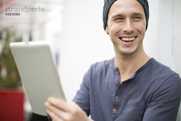Porträt eines lächelnden jungen Mannes mit digitalem Tablett