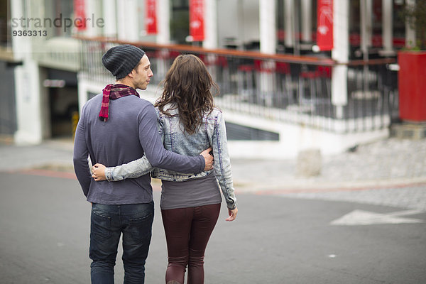 Junges Paar geht Arm in Arm auf der Straße.