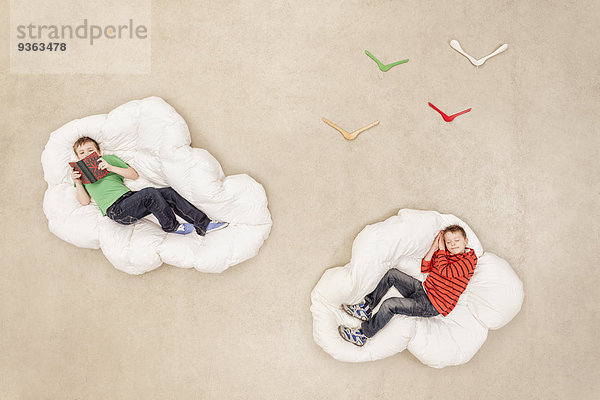 Auf Wolken liegende Jungen lesen und schlafen