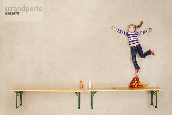 Mädchen beim Balancieren auf einem Apfelstapel