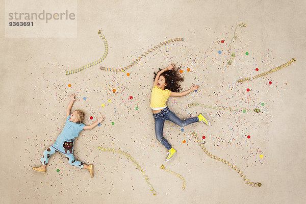 Mädchen springen zwischen Luftschlangen und Konfetti.