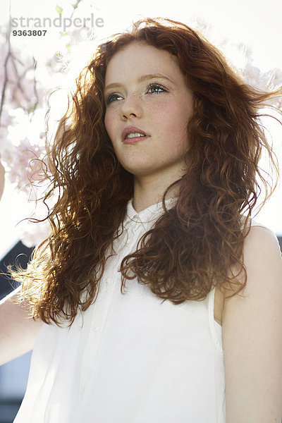 Porträt eines Mädchens mit gelockten roten Haaren in weißem Kleid
