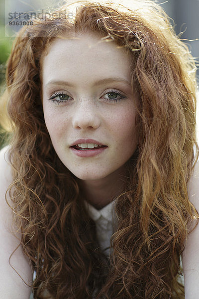 Porträt eines Mädchens mit lockigen roten Haaren und Sommersprossen
