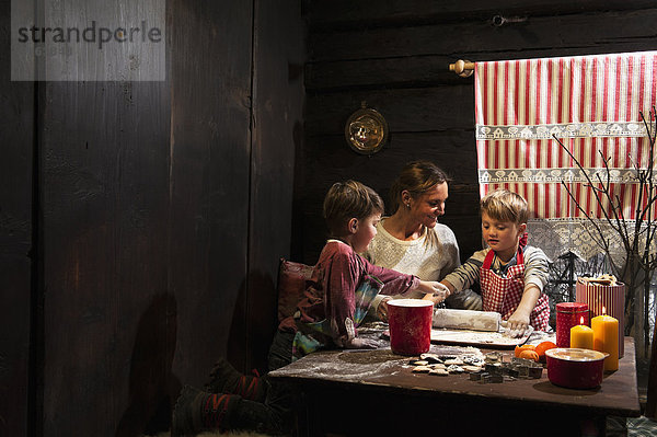 Mutter und ihre zwei kleinen Söhne backen in der Adventszeit Weihnachtsplätzchen.