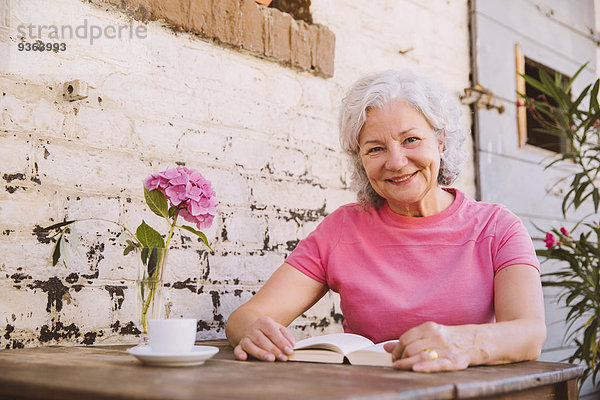 Deutschland  Nordrhein-Westfalen  Bornheim  Seniorin im Hof sitzend  Kaffee trinkend