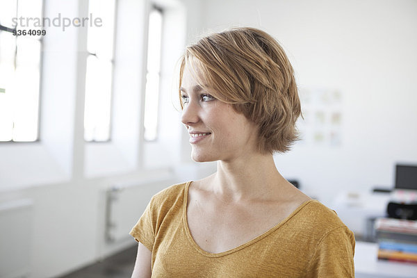 Porträt einer lächelnden jungen Frau in einem Kreativbüro