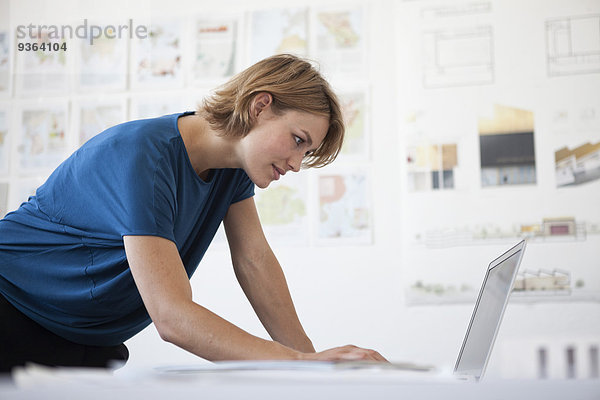 Porträt einer jungen Frau mit Laptop im Kreativbüro