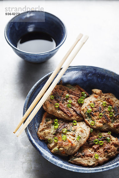 Japanische Buchweizenpfannkuchen mit Tofu und Gemüse  Essstäbchen und Schale mit Sojasauce
