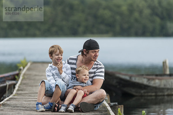 Deutschland  Rheinland-Pfalz  Laacher See  Vater sitzend mit zwei Söhnen am Steg