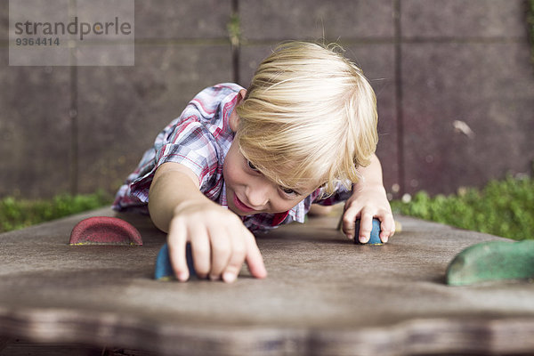 Portrait eines kleinen Jungen beim Klettern auf einem Spielplatz