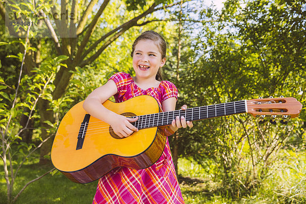 Mädchen spielt Gitarre im Garten
