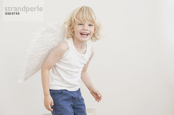 Porträt eines lachenden kleinen Jungen mit Winkelflügeln