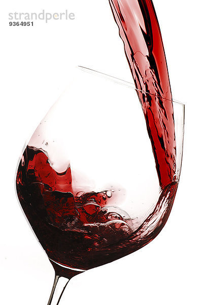 Rotwein wird in ein Weinglas gegossen