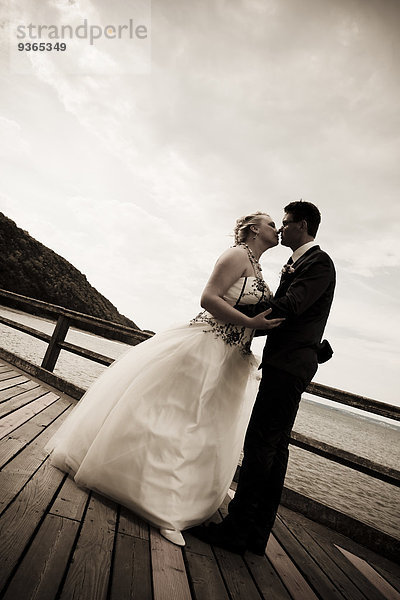 Brautpaar küsst sich vor der Ostsee