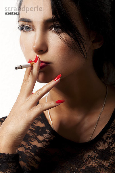 Porträt der rauchenden jungen Frau mit rotem Nagellack