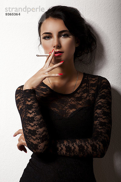 Porträt der rauchenden jungen Frau mit rotem Nagellack