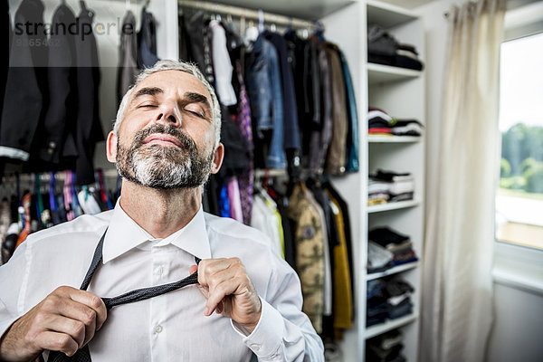 Geschäftsmann bindende Krawatte an seinem begehbaren Kleiderschrank