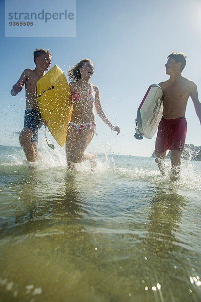 Drei Teenager mit Surfbrettern am Ufer des Meeres