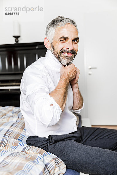 Porträt eines lächelnden Geschäftsmannes mit Krawatte im Schlafzimmer