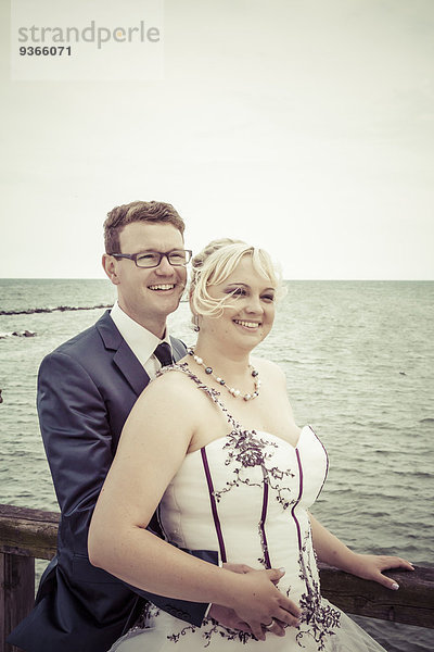 Porträt des glücklichen Brautpaares vor dem Meer