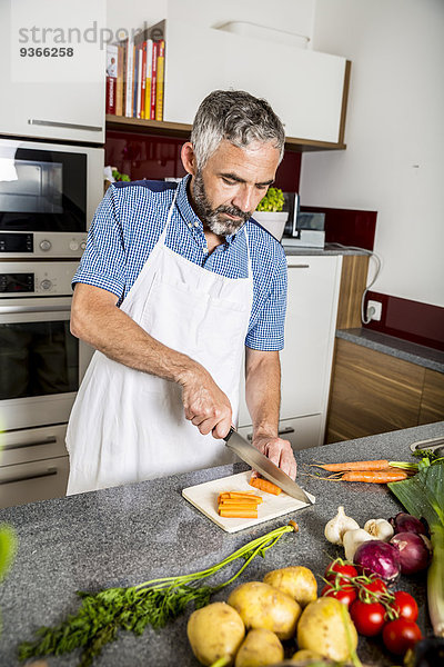 Österreich  Mann in der Küche zerkleinert Karotten