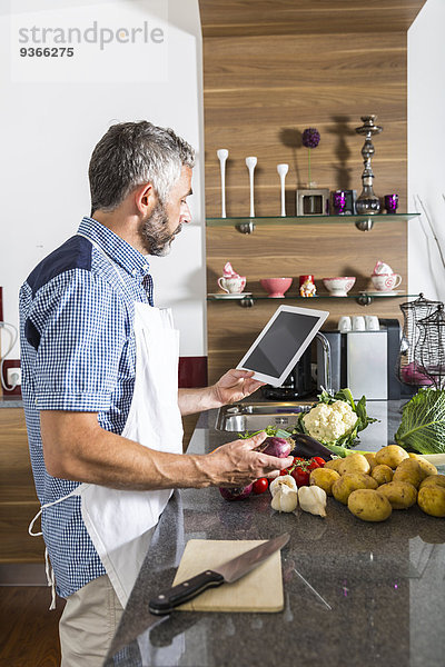 Österreich  Mann in der Küche mit digitaler Tablette zur Zubereitung von Speisen