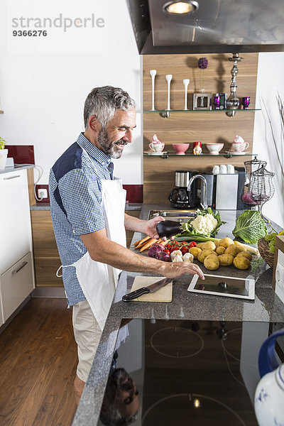 Österreich  Mann in der Küche mit digitaler Tablette zur Zubereitung von Speisen