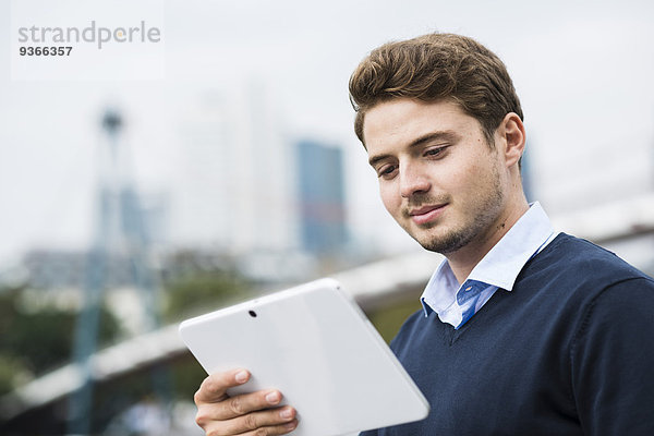 Deutschland  Hessen  Frankfurt  Portrait eines lächelnden jungen Mannes mit digitalem Tablett