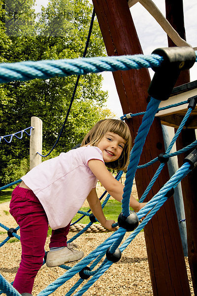 Kleines Mädchen beim Klettern auf dem Spielplatz