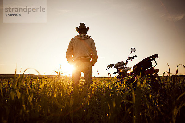 stehend Mann Feld Motorrad