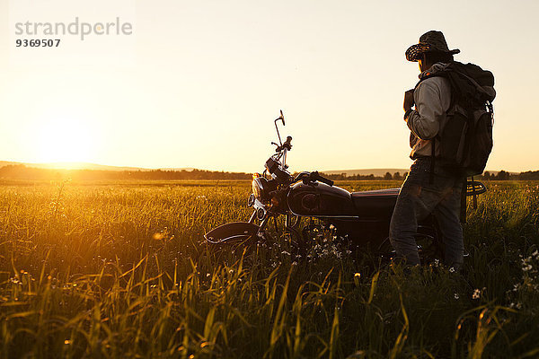 stehend Mann Feld Motorrad