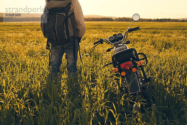 stehend Mann Feld Motorrad