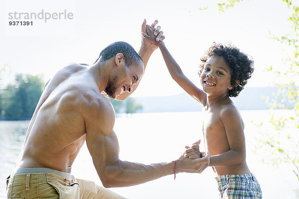 Vater spielt mit seinem Sohn  ringt mit ihm an einem See.