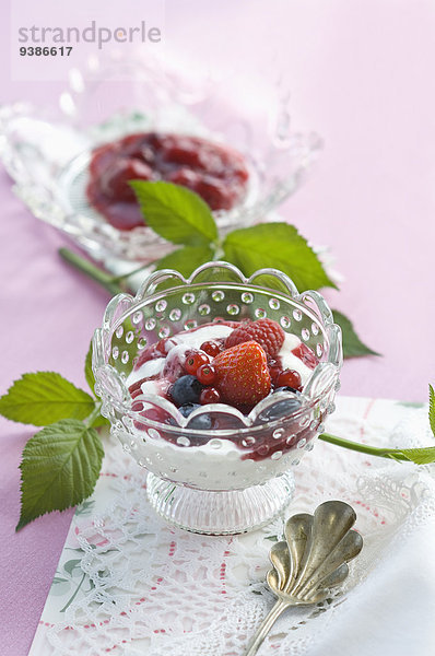 Rote Grütze mit frischen Früchten in einer Glasschale