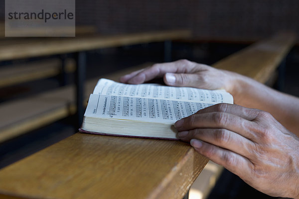 Hände auf einem Gesangbuch in der Kirche